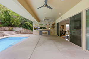 Covered outdoor patio featuring a swimming pool, stone accent wall, recessed lighting, and dual ceiling fans