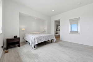Bedroom featuring light wood-finish flooring, recessed lighting, and wall-mounted sconces