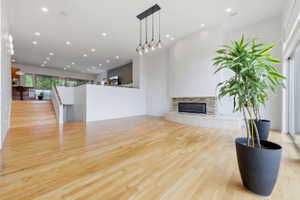 Spacious interior featuring wood-finish flooring, a contemporary fireplace with a stone surround, recessed lighting, and a modern multi-light pendant fixture