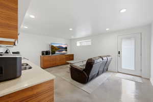 Spacious living area featuring polished concrete flooring, recessed lighting, and a built-in wood-finish media console