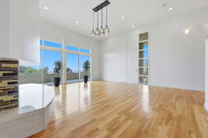 Spacious room featuring wood-finish flooring, a contemporary multi-globe chandelier, and recessed lighting