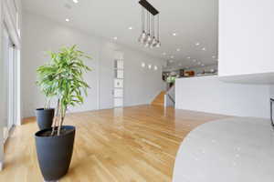 Expansive living space featuring light wood-finish flooring, recessed ceiling lights, and abundant natural light from large sliding glass doors