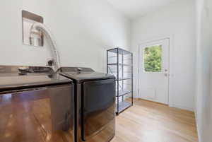Laundry area featuring wood-finish flooring, a white paneled door with a clear glass insert, and clean white walls