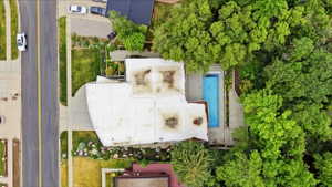 Property featuring a flat roofline, an integrated swimming pool, and extensive surrounding mature trees