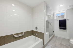 Modern bathroom featuring a bathtub with chrome fixtures and a glass-enclosed shower with a built-in bench