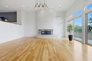 Open-concept living space with light wood flooring and a modern fireplace featuring a stone surround and hearth