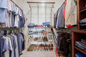 Custom closet system featuring multiple hanging rods, wire shelving, and built-in wood-finish shelving units