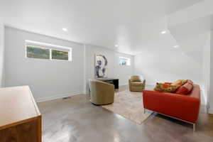 Spacious room featuring concrete flooring, recessed lighting, white walls, and multiple egress windows