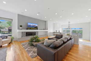 Open-concept living area featuring hardwood flooring, recessed lighting, and a modern fireplace with mosaic tile surround