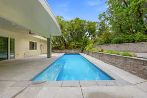 Rectangular swimming pool surrounded by concrete decking and tiered retaining walls with integrated landscaping