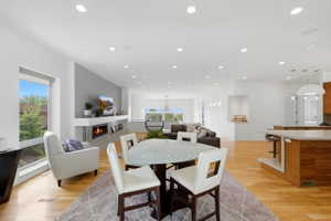 Open concept living space featuring light wood-finish flooring, recessed lighting, and a modern fireplace with a stone surround