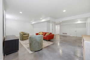 Spacious lower-level room featuring polished concrete flooring, recessed lighting, and crisp white walls