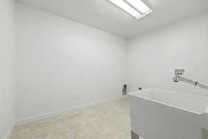 Laundry room featuring a utility sink with an attached faucet, tile flooring, and white walls