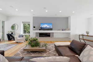 Bright living area featuring wood-finish flooring, recessed lighting, and a contemporary fireplace with a mosaic tile surround