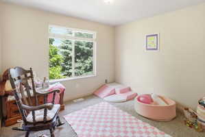 Spacious room featuring a large window, neutral wall paint, and light-colored carpet