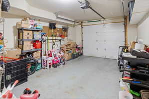Garage space featuring a white panel door and concrete flooring