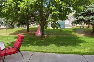 Expansive green lawn with mature trees and a chain-link fence