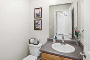 Bathroom vanity featuring an oval sink with chrome faucet, a stone-finish countertop, and wood-finish cabinetry