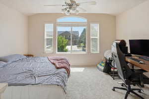 Carpeted room featuring a large arched window with side windows, a ceiling fan with light fixture, and vaulted ceilings