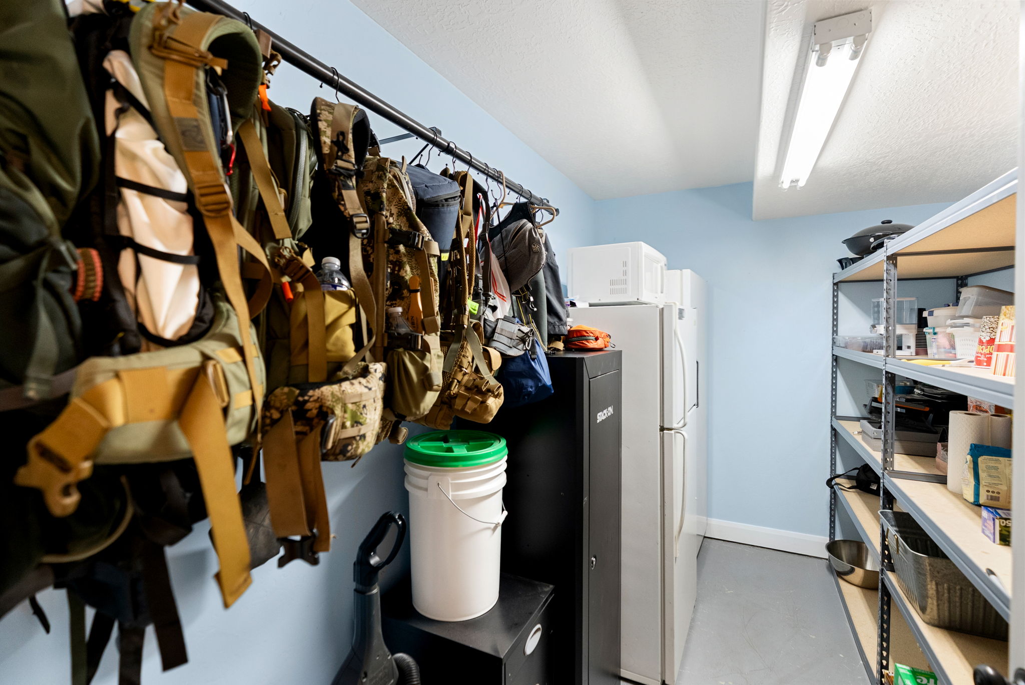 Dedicated storage area featuring expansive shelving units, two full-size refrigerators, and overhead fluorescent lighting