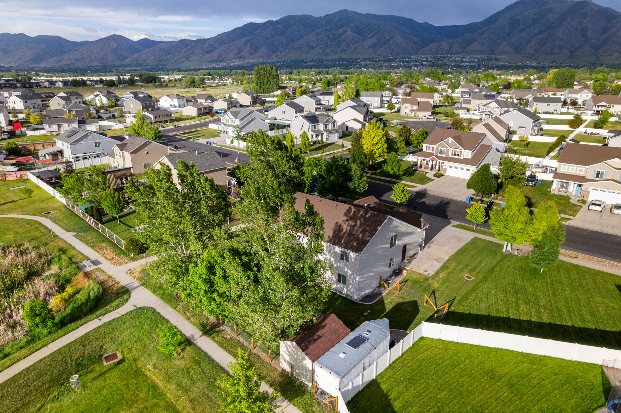 Residential neighborhood featuring a paved pathway system, mature trees, and mountain backdrop