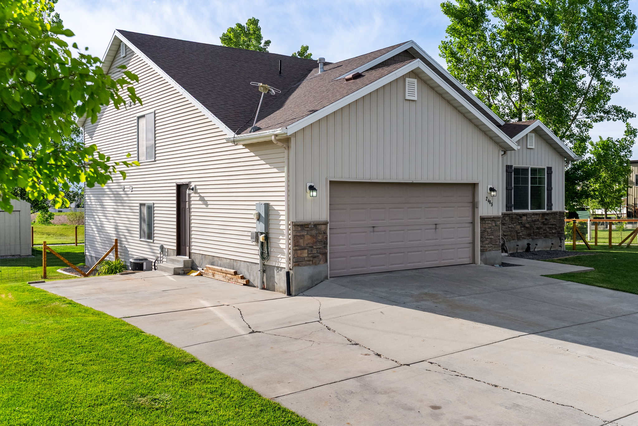 Exterior featuring light-colored horizontal siding, a dark roof, and a two-car garage with a complementary door