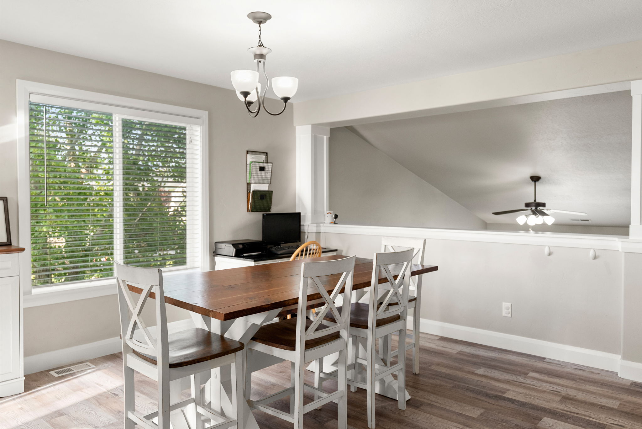 Dining area with wood-finish flooring, a large window with blinds, and a contemporary chandelier