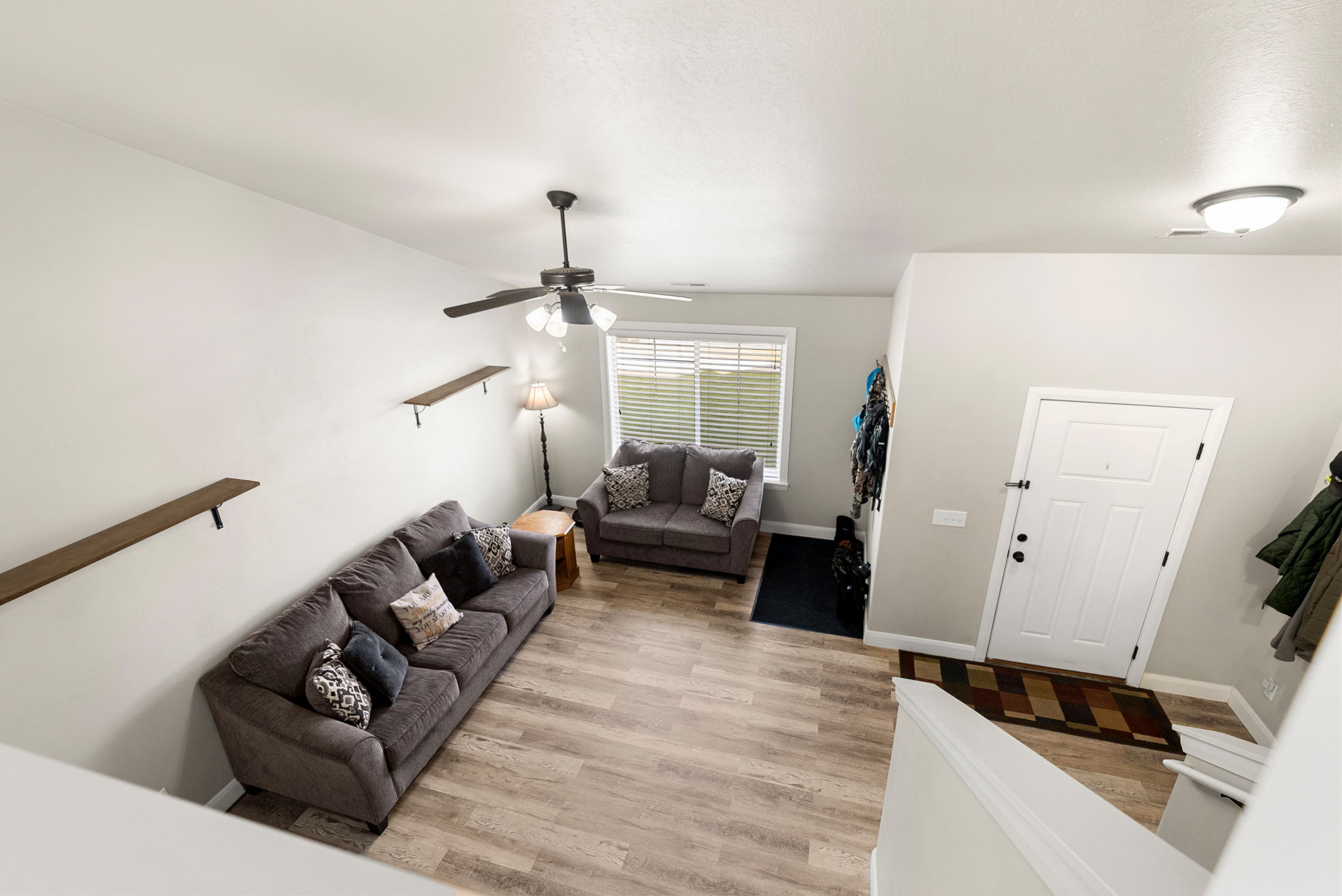 Open-concept living area featuring wood-finish flooring, a ceiling fan with integrated lighting, and high ceilings