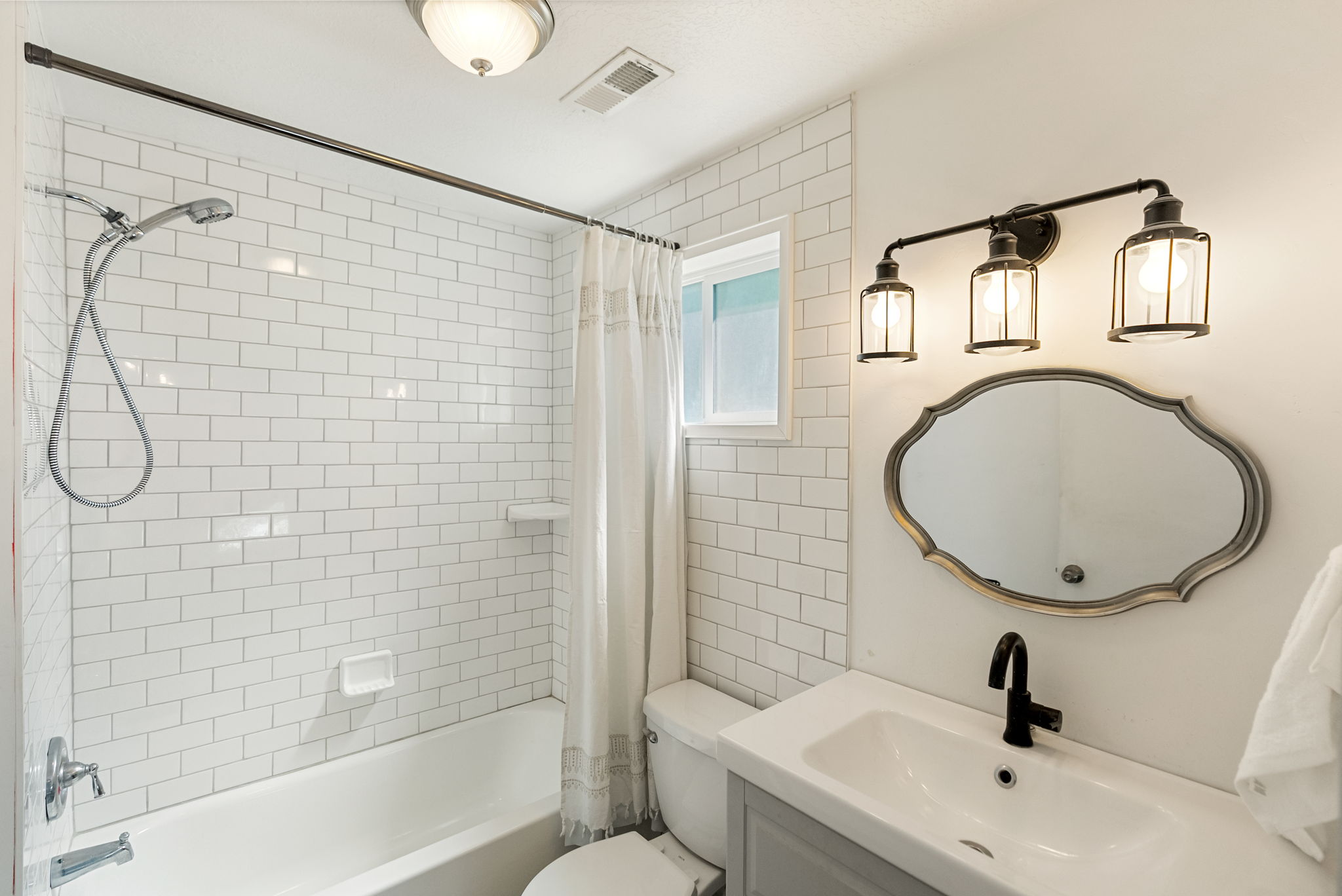 Bathroom featuring subway tile shower surround, integrated bathtub, and a vanity with a white basin sink