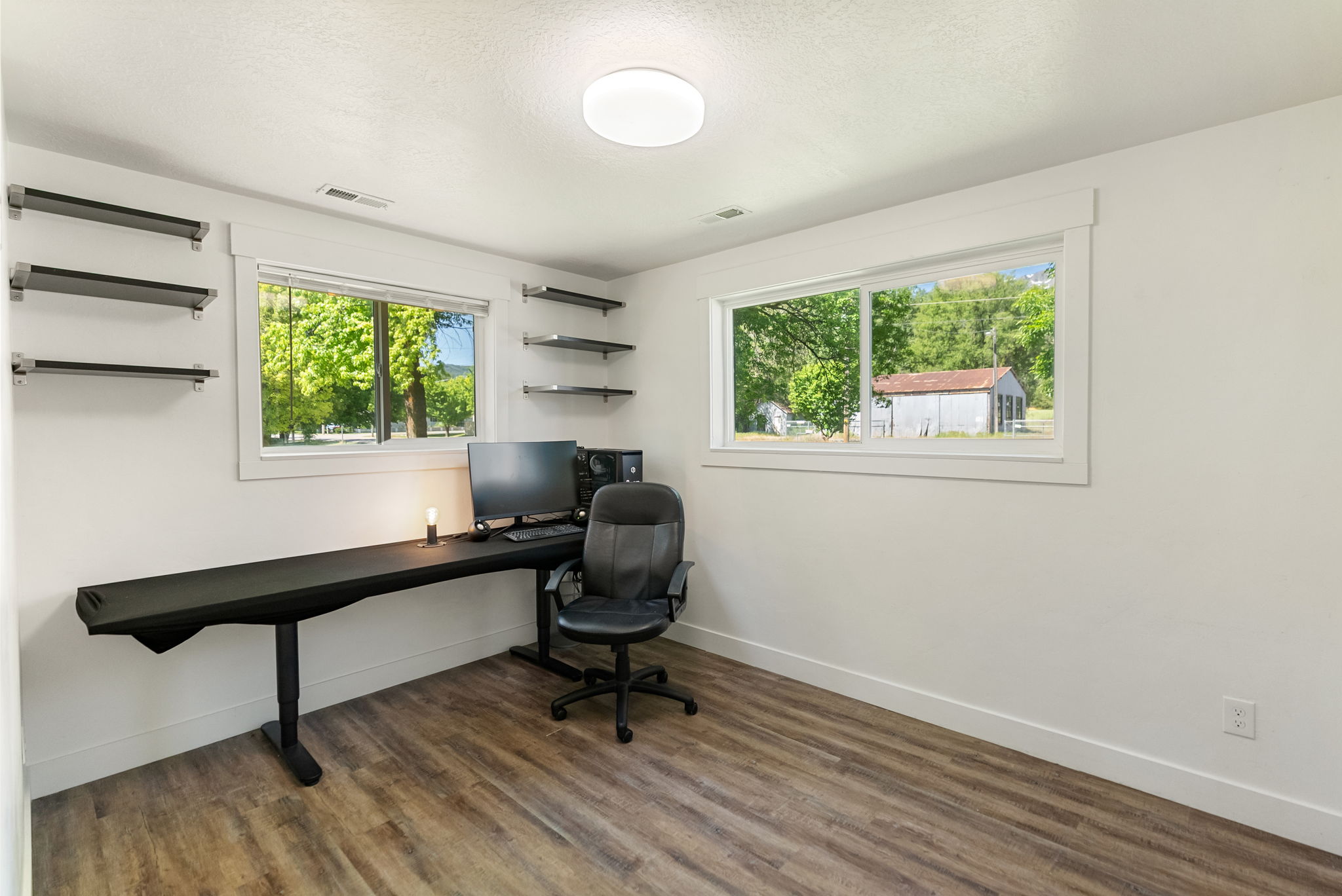 Spacious room with wood-finish flooring and multiple windows providing natural illumination
