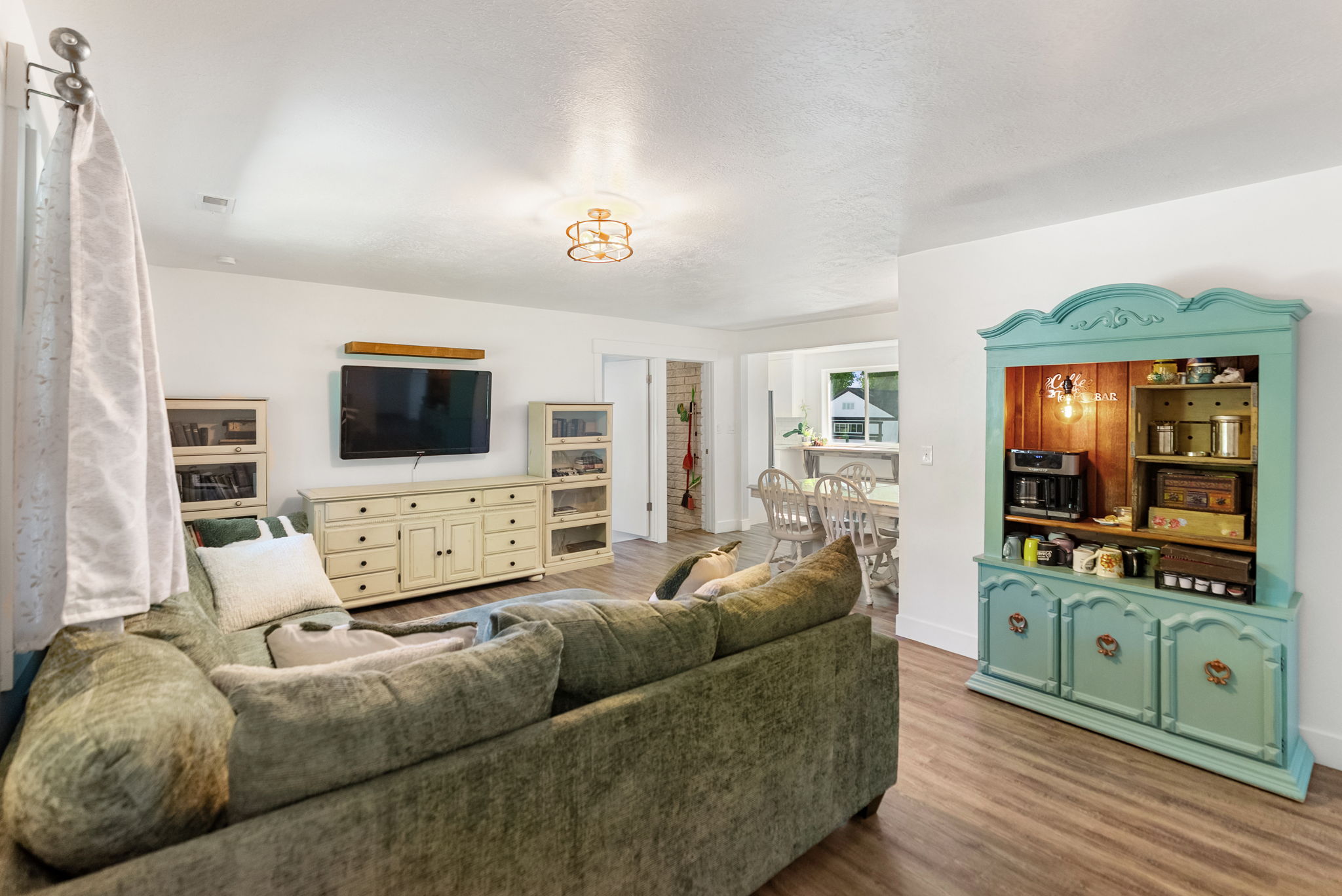 Bright living area featuring wood-finish flooring, a decorative ceiling light fixture, and a built-in display cabinet