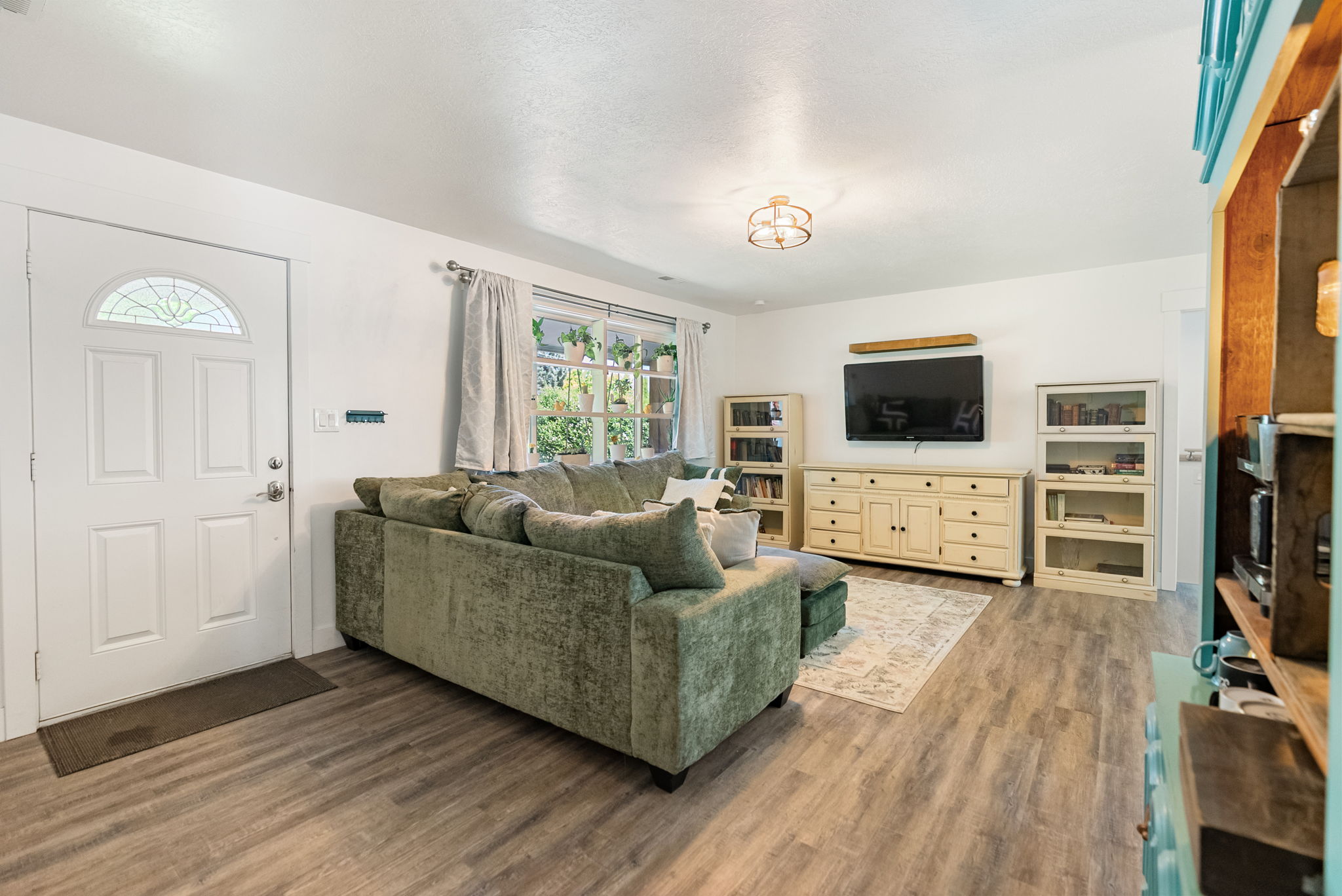 Living area featuring wood-finish flooring, a decorative entry door with an arched glass insert, and abundant natural light from multiple windows