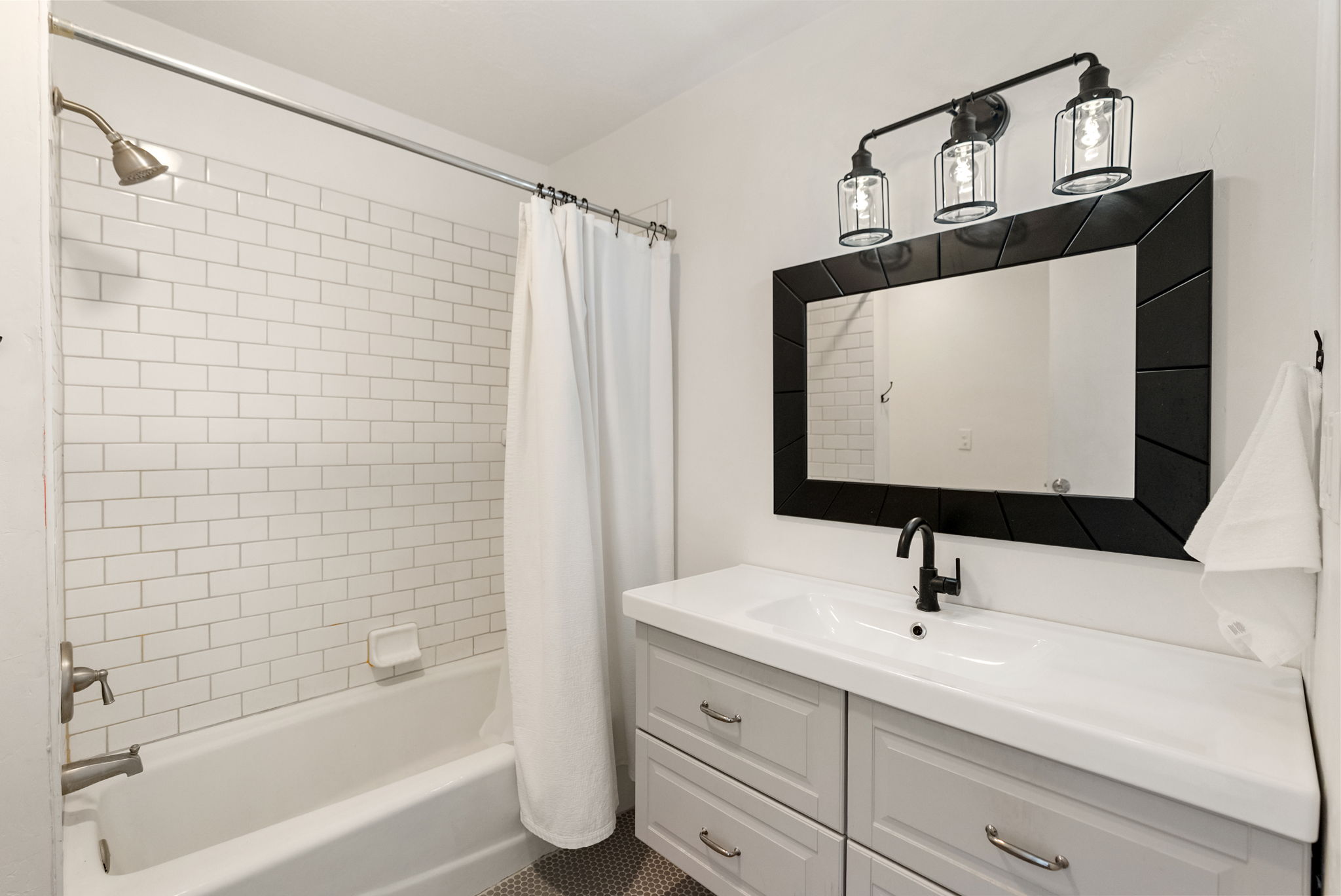 Bathroom featuring a vanity with an integrated sink, a black framed mirror, and a three-light fixture