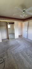 Carpeted room featuring a ceiling fan with integrated lighting, a mirrored closet door, a closet with a built-in rod, and a doorway