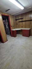 Room featuring wood paneling and a built-in L-shaped desk with red cabinetry