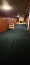 Spacious room featuring green carpeting, wood paneling, a built-in bar, and a fireplace with integrated shelving