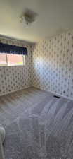 Carpeted interior room with patterned wallpaper