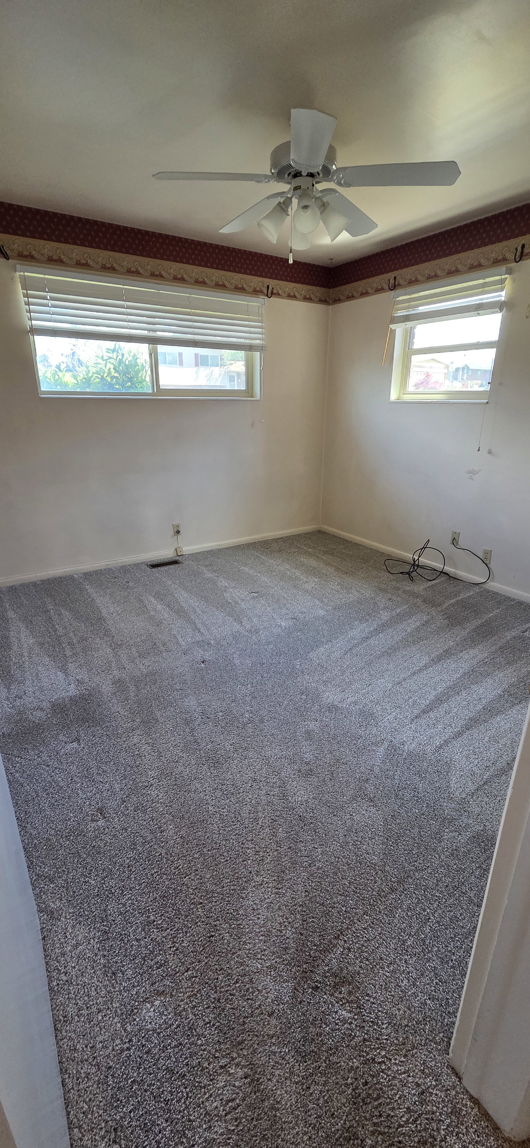 Room featuring light-toned walls, grey carpet, and a ceiling fan with integrated lighting