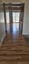 Wood-finish flooring extending from the entryway through to a rear room, featuring sliding glass doors and a view of the outdoor patio