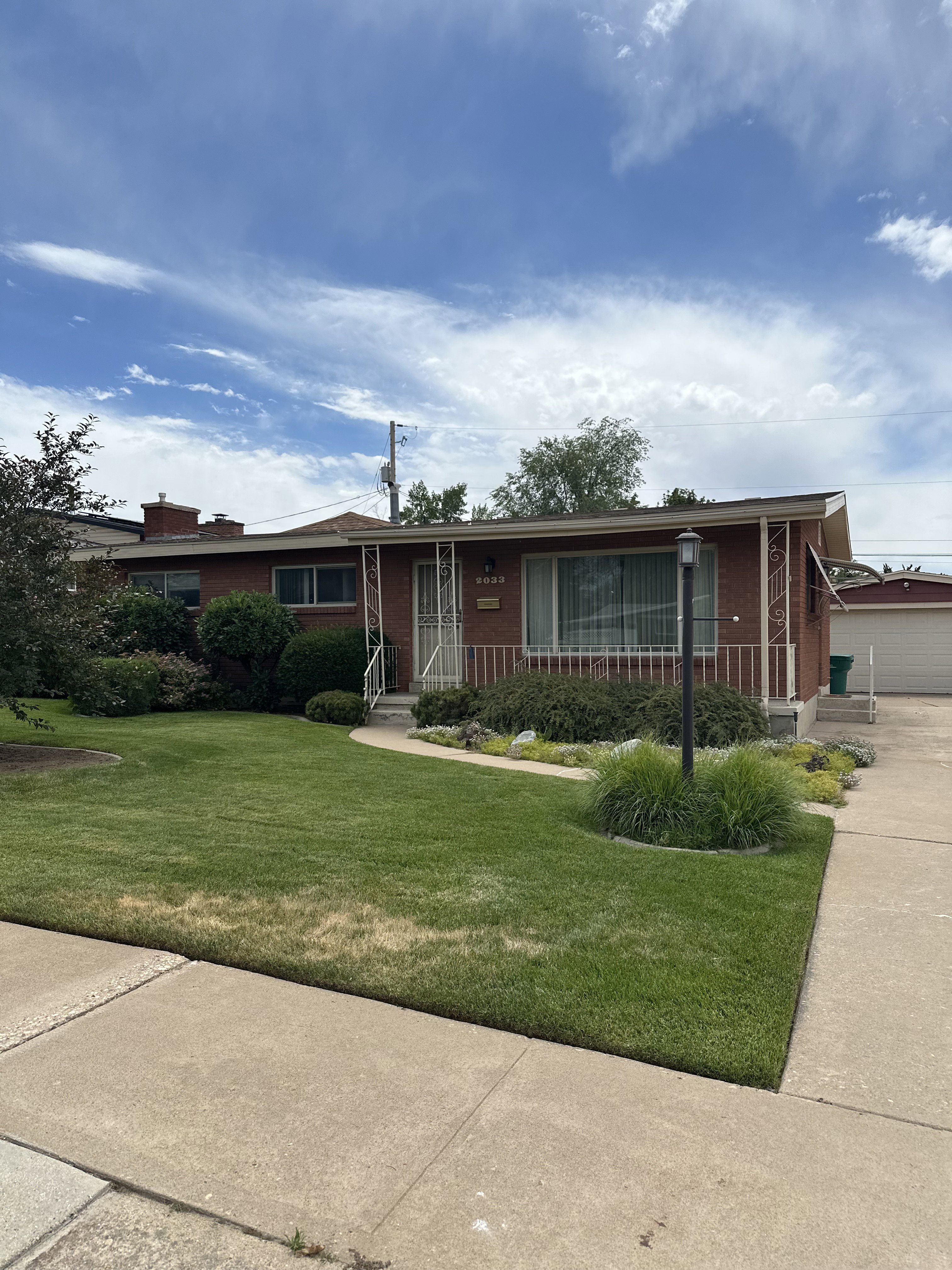 Brick exterior featuring a front lawn with established landscaping and a curved concrete walkway