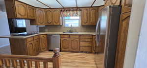 Kitchen featuring wood cabinetry, stainless steel appliances, a built-in cooktop, and light-toned countertops