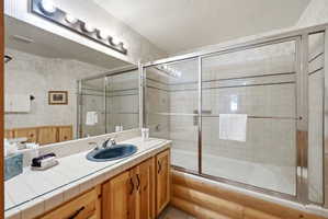Bathroom featuring a vanity with a blue basin sink, tile countertop, and wood-finish cabinetry