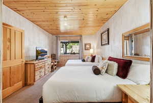Bedroom featuring a natural wood plank ceiling, textured wall finish, and a large window with wood trim