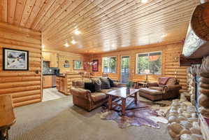 Open-concept living area featuring log-style walls and a wood-paneled ceiling