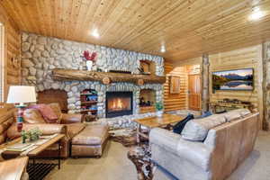 Expansive stone fireplace with a substantial log mantel, flanked by built-in shelving and a recessed hearth