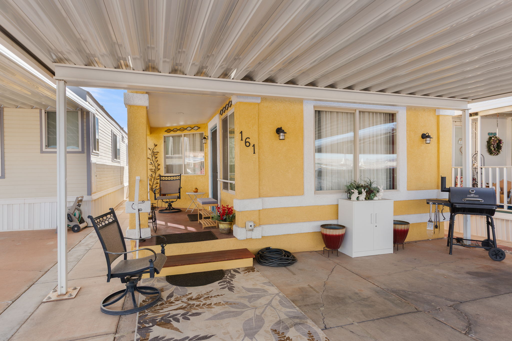 Covered patio area featuring a concrete slab, a small raised porch with steps, and exterior wall sconces
