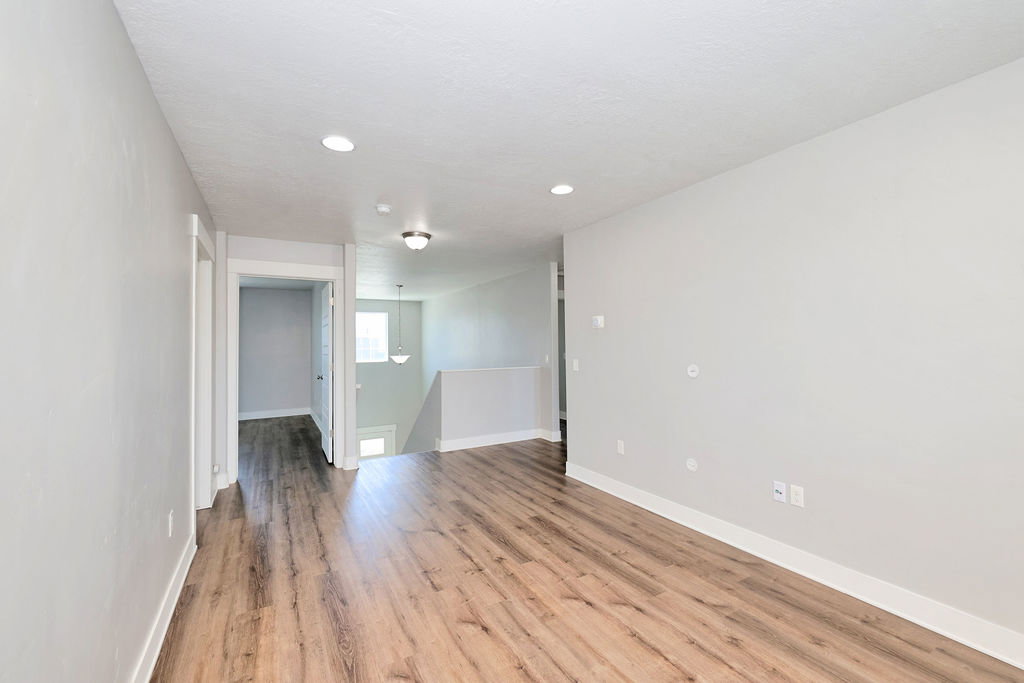 Open living area featuring wood-finish flooring, recessed lighting, and a neutral color palette