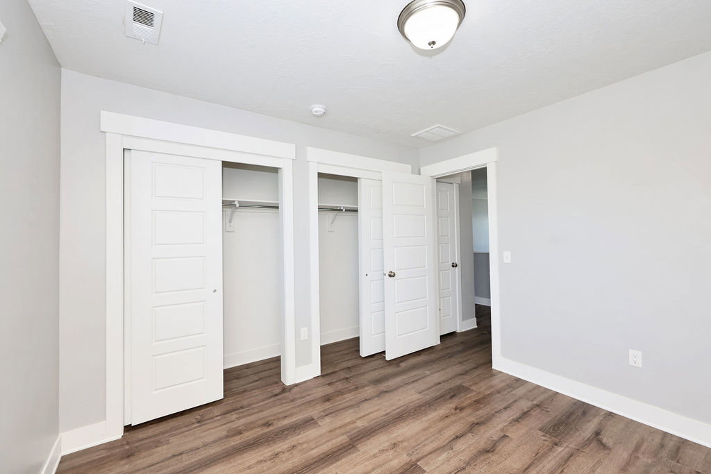 Room featuring wood-finish flooring, light grey walls, and white trim