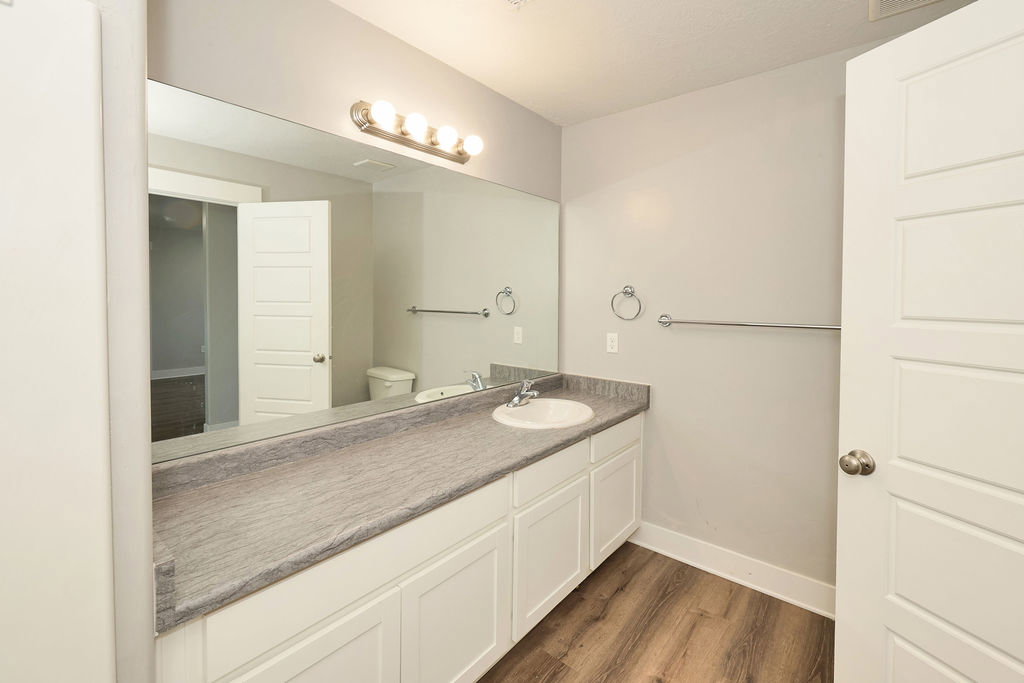 Bathroom featuring a long vanity with a single basin sink and a stone-look countertop
