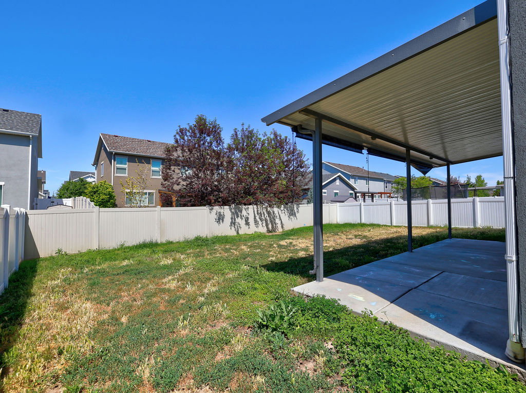 Expansive backyard featuring a covered patio, concrete slab, and perimeter fencing